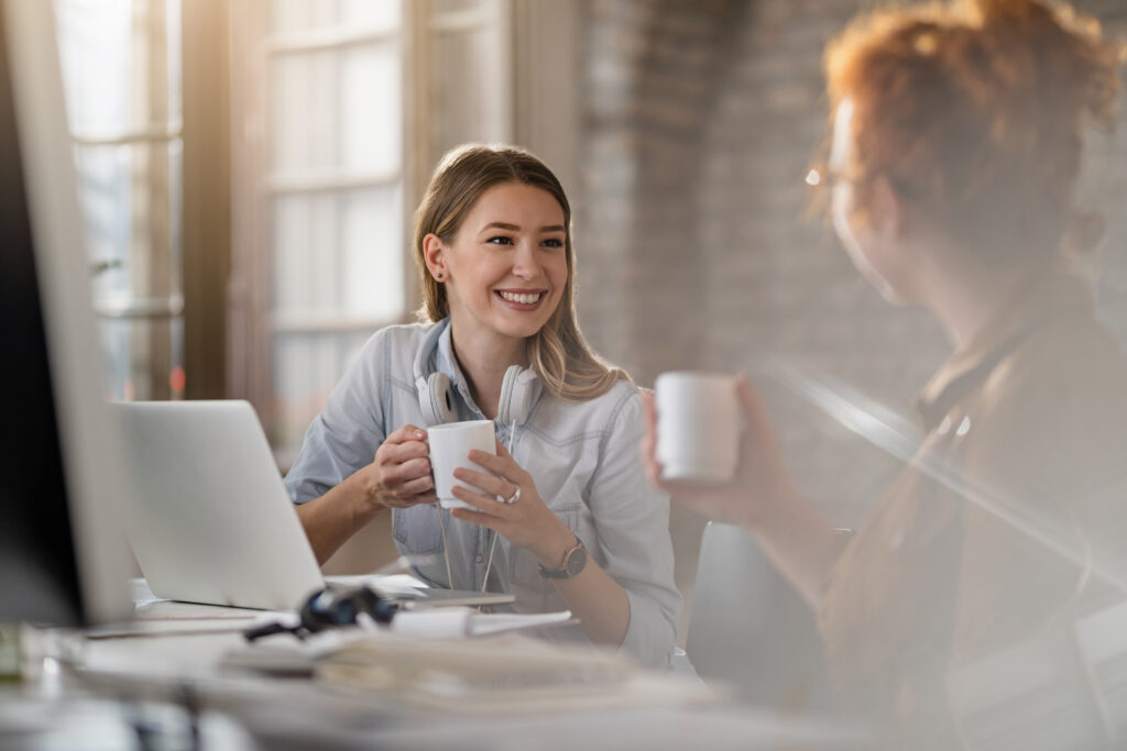 young smiling businesswoman her female colleague communicating while having coffee break office